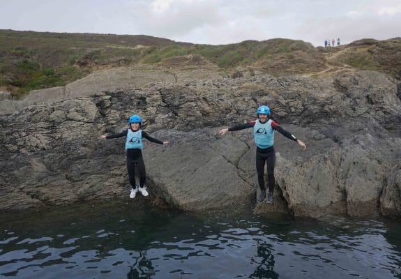 Two people cliff jumping during coasteering in Croyde North Devon